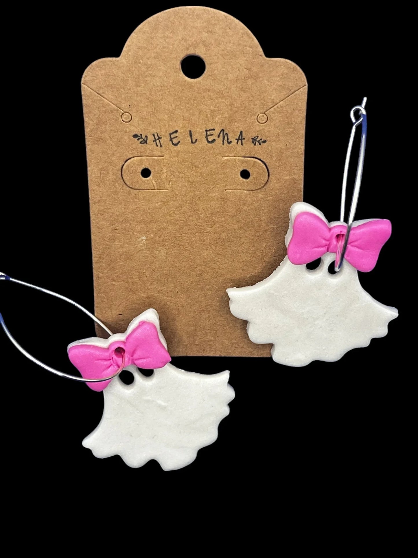 Helena’s Artisan & Gift Co. white ghost hoop earrings with pink bows on a branded kraft paper display card.