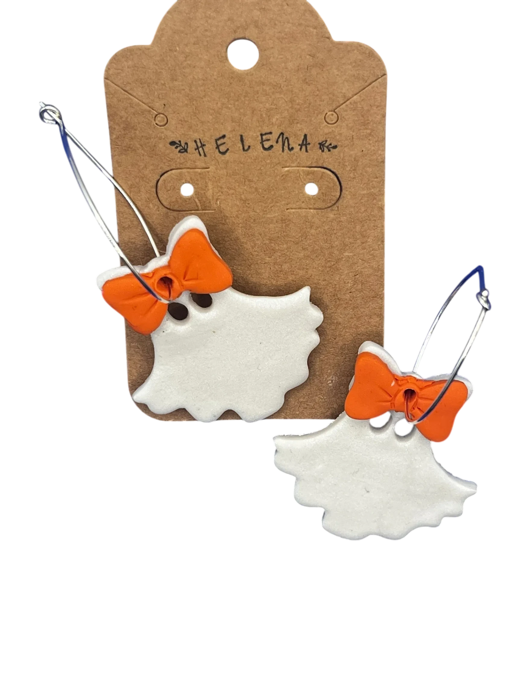 Helena’s Artisan & Gift Co. white ghost hoop earrings with orange bows on a branded cardboard display card.